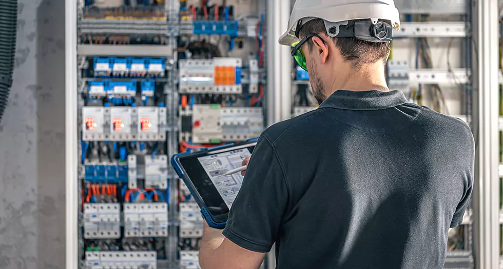 Elektriker bei er Arbeit Elektriker bei er Arbeit mit dem Phasenprüfer an einem Stromverteilerkasten
